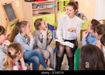Giovane insegnante femminile ha causato sorpresa di bambini con storia a. lezione in classe Foto Stock