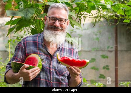 Ritratto di contadino maschio con bearded maturo con cocomero maturo, concetto di raccolto proprio, fuoco selettivo Foto Stock