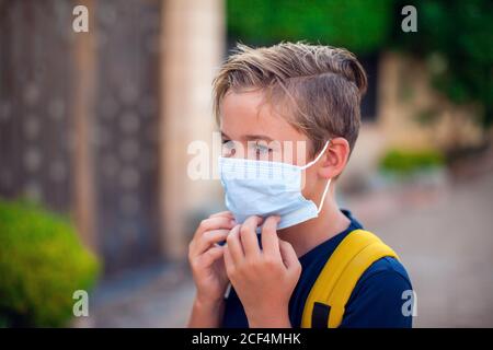 Pupillo con maschera facciale che rimane all'aperto. Torna a scuola in coronavirus pamdemid Foto Stock