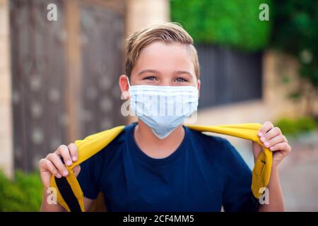 Pupillo con maschera facciale che rimane all'aperto. Torna a scuola in coronavirus pamdemid Foto Stock