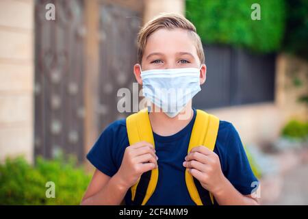 Pupillo con maschera facciale che rimane all'aperto. Torna a scuola in coronavirus pamdemid Foto Stock