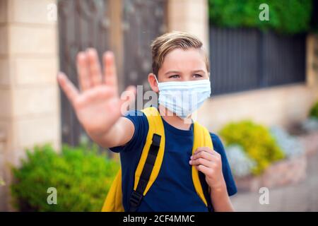 Pupillo con maschera facciale che rimane all'aperto. Torna a scuola in coronavirus pamdemid Foto Stock