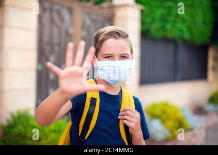 Pupillo con maschera facciale che rimane all'aperto. Torna a scuola in coronavirus pamdemid Foto Stock