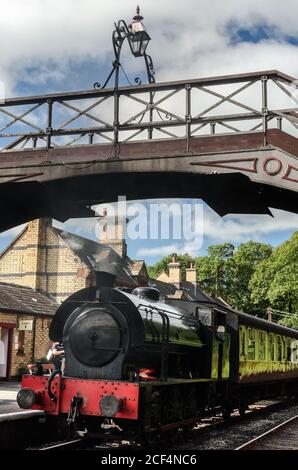 Steam Train Repulse, sulla ferrovia, attende sotto un ponte alla stazione di Haverthwaite su una linea ferroviaria di diramazione nel Lake District (UK) Foto Stock