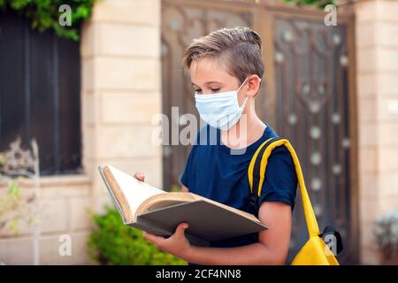 Pupillo con maschera facciale che rimane all'aperto. Torna a scuola in coronavirus pamdemid Foto Stock