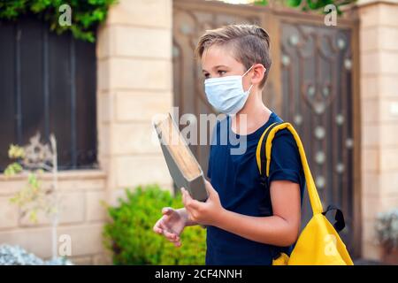 Pupillo con maschera facciale che rimane all'aperto. Torna a scuola in coronavirus pamdemid Foto Stock