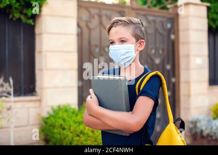 Pupillo con maschera facciale che rimane all'aperto. Torna a scuola in coronavirus pamdemid Foto Stock