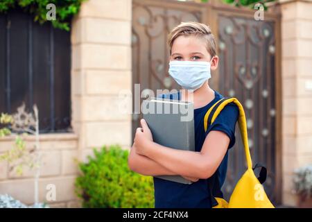 Pupillo con maschera facciale che rimane all'aperto. Torna a scuola in coronavirus pamdemid Foto Stock