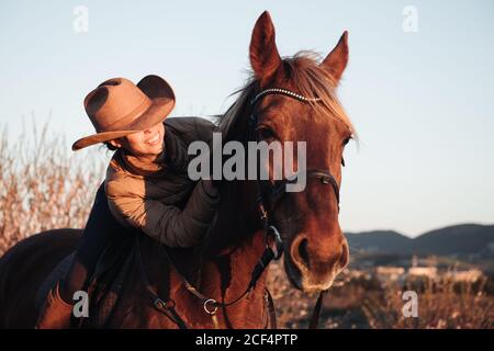 Donna a cavallo contro il cielo del tramonto sul ranch Foto Stock