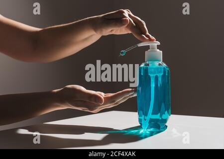 Il prodotto non deve essere rivolto verso la persona che tira le mani per il sapone liquido blu di plastica flacone con dispenser bianco all'interno situato su tavolo bianco con ombra Foto Stock