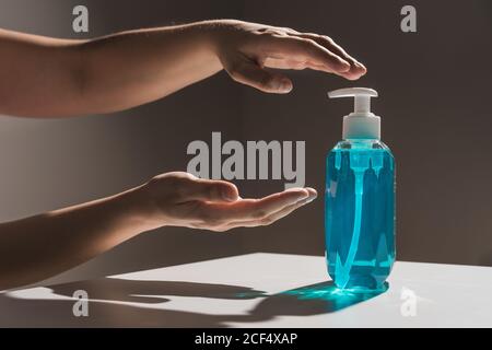 Il prodotto non deve essere rivolto verso la persona che tira le mani per il sapone liquido blu di plastica flacone con dispenser bianco all'interno situato su tavolo bianco con ombra Foto Stock