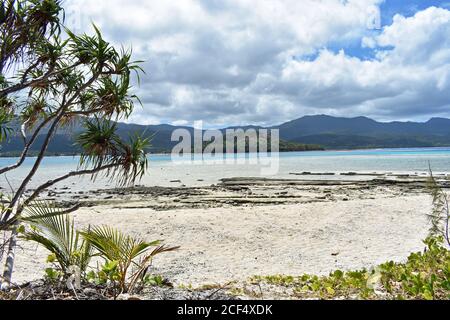 Guardando oltre il fogliame tropicale e la spiaggia incontaminata per le montagne sulla principale isola di Anetyum da Mystery Island, Vanuatu nel Sud Pacifico. Foto Stock