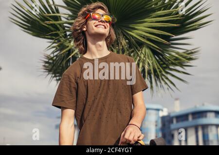 Blonde curly uomo felice su street palm al tramonto Foto Stock