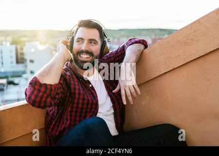 Un ritratto di un giovane mentre ascolti la musica all'esterno. È sorridente e felice Foto Stock