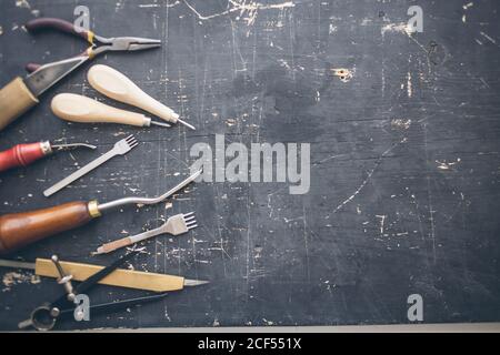 Posa piatta di attrezzo di lavorazione di cuoio su prodotto di pelle di vera pelle su sfondo di legno. Con copyspase Foto Stock