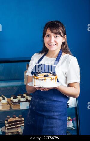 Perfetto per la colazione. Un colpo di una giovane donna splendida che tiene un cestino pieno di croissant appena sfornati che sta vendendo al suo copyspace della panetteria Foto Stock