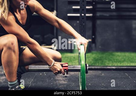 Vista laterale della Donna muscolare preparazione per l'allenamento con peso pesante in palestra Foto Stock