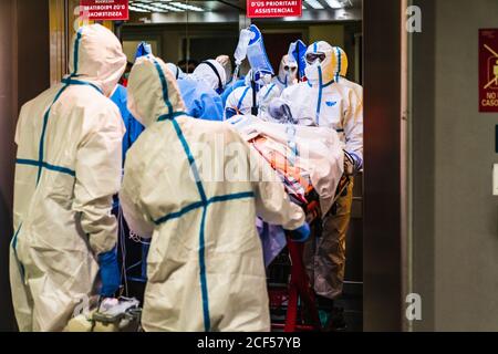 Gruppo di medici irriconoscibili che indossano l'uniforme protettiva mentre prendono il paziente con virus da ascensore in ospedale Foto Stock