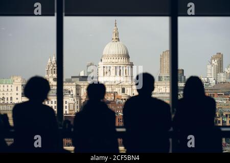 Silhouette con vista posteriore dei viaggiatori che si trovano vicino alla finestra del punto di osservazione E ammirando la vista della Cattedrale di San Paolo a Londra Foto Stock