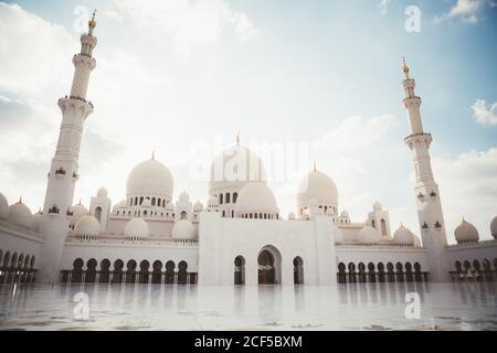 Bella moschea bianca con cupole e minareti sotto il cielo blu luminoso, Dubai Foto Stock