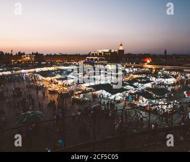 Marocco - Aprile 08 2019: Folla di persone irriconoscibili che camminano tra tende illuminate sulla piazza del mercato durante il tramonto Foto Stock