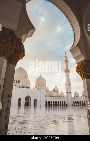 Bella moschea bianca con cupole e minareti sotto il cielo blu luminoso, Dubai Foto Stock