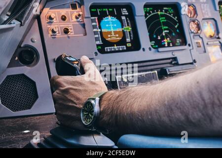 Crop anonimo pilota maschile che esegue il controllo manuale di aerei contemporanei durante il volo Foto Stock