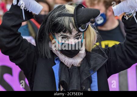 Un manifestante vestito da clown durante la dimostrazione.Extinction Rebellion Carnevale della corruzione manifestanti marcia da Piazza del Parlamento a Trafalgar Square dove hanno tenuto una protesta seduta giù, la polizia si è trasferita e ha fatto arresti. Gli attivisti chiedono che coloro che sono al potere intraprendano azioni in materia di clima e ambiente. Foto Stock