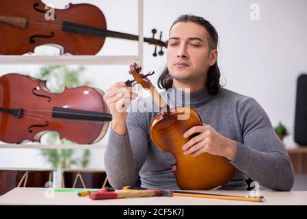 Giovane uomo riparatore che ripara il violino in officina Foto Stock