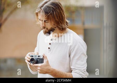 Giovane uomo bearded bello in vestiti casual scattando foto dentro via Foto Stock