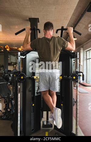 Ragazzo muscolare che fa tirare su macchina da ginnastica Foto Stock