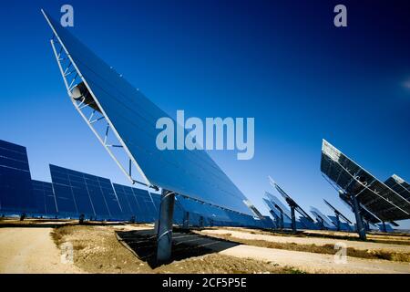 Moderni pannelli solari installati sul campo contro il cielo blu senza nuvole nella centrale fotovoltaica Foto Stock