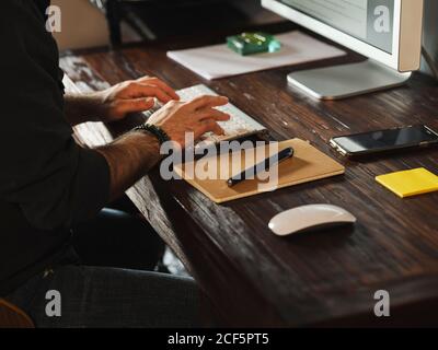 dettaglio delle mani dell'uomo che lavorano a casa con il computer tramite internet digitando sul computer Foto Stock