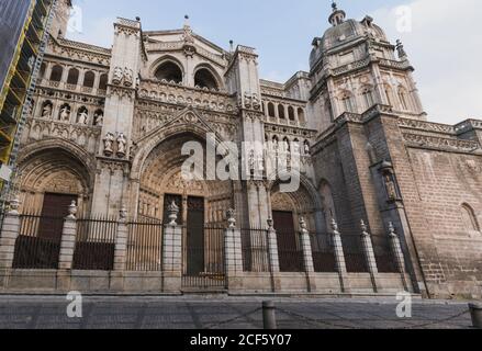 Da sotto dell'esterno di bella pietra gotica medievale di stile Costruzione della Cattedrale Primate di Santa Maria di Toledo in Spagna contro il cielo blu nuvoloso Foto Stock