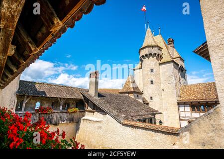 Ampio angolo di vista del castello di Aigle dal muro di passeggiata con Fiori e la torre principale e cielo blu chiaro in Aigle Vaud Svizzera Foto Stock