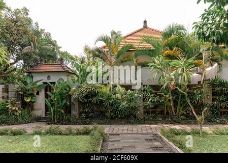 Passerella in pietra che conduce all'ingresso di cottage circondato da esotici Piante in giornata di sole a Bali Foto Stock