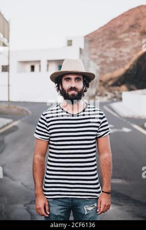 Elegante giovane uomo in t-shirt a righe in piedi su strada e. Sorridi con la macchina fotografica a la Restinga, sull'isola delle Canarie Foto Stock