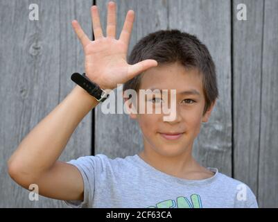 Misto-gara pre-teen boy (Asia orientale e caucasico) mostra con la sua mano destra il segno cinese per il numero 5 (serie di foto: Immagine n. 5 di 10). Foto Stock