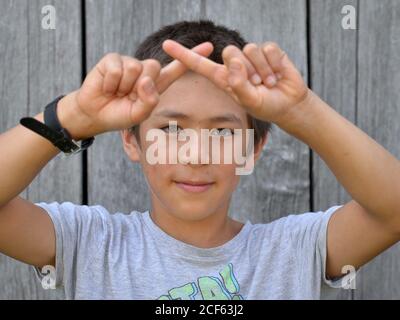 Misto-gara pre-teen boy (Est Asiatico e Caucasico) mostra con entrambe le mani il segno cinese per la mano numero 10 (foto serie: Immagine n. 10 di 10). Foto Stock