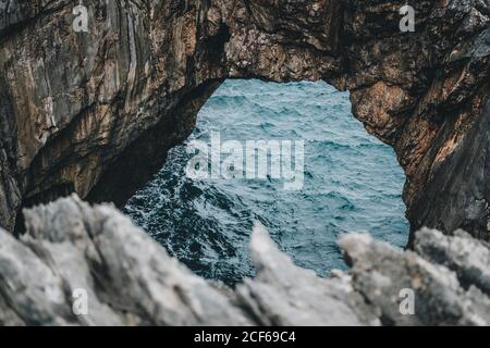 Vista mozzafiato delle scogliere rocciose con arco naturale e bella laguna in giorno nuvoloso Foto Stock