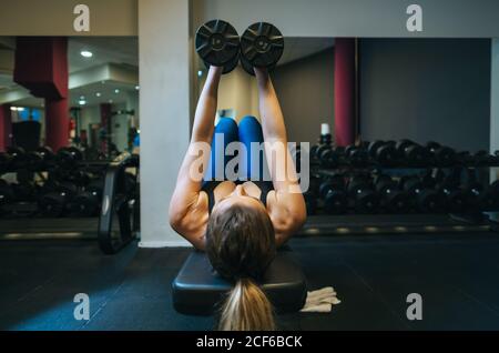 Donna che solleva manubri su panca Foto Stock