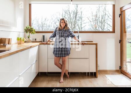Bella e giovane donna nella cucina della sua casa, guardando la macchina fotografica Foto Stock
