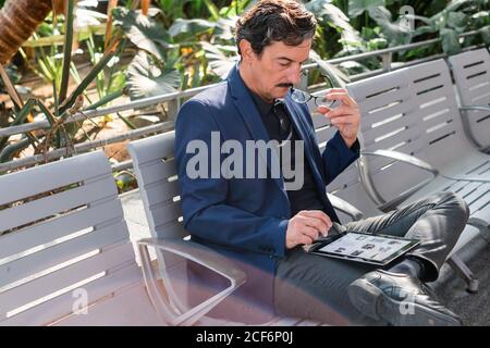 Uomo bello e anziano che usa il tablet digitale all'aperto Foto Stock