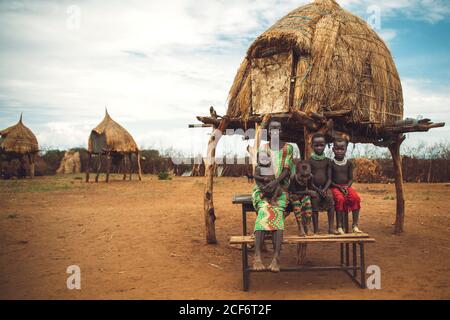 Omo Valley, Etiopia - 08 novembre 2018: Donne e bambini della tribù Nyangatom seduti vicino alla capanna di paglia nel villaggio. Omo Valley, Etiopia Foto Stock