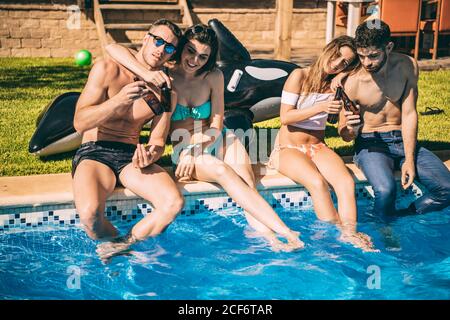 Giovani amici che beve in piscina Foto Stock