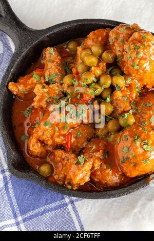 Da sopra padella calda con deliziose polpette cotte e verde piselli su tovaglia bianca Foto Stock