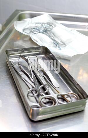 Da sopra vassoio in acciaio con forbici chirurgiche sterili e pinzette su tavolo metallico in clinica Foto Stock