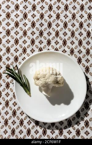 Bouquet crudo di cavolfiore con rosmarino dall'alto con luce solare. Disposizione piatta. Vista dall'alto Foto Stock