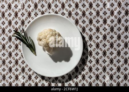 Bouquet crudo di cavolfiore con rosmarino dall'alto con luce solare. Disposizione piatta. Vista dall'alto Foto Stock