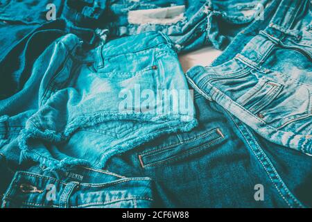 Jeans veloce moda tessile industria tonnellate di paia di pantaloni prodotti ogni anno andando a sprecare. Closeup di molti tessuti denim diversi di indaco blu Foto Stock